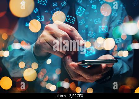 Newsletter e email marketing, uomo d'affari che invia grandi quantità di messaggi utilizzando il suo smartphone, focus selettivo Foto Stock