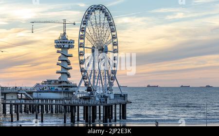 Una foto panoramica della ruota panoramica e del Piertoren sul molo di Scheveningse con splendide nuvole al tramonto sullo sfondo Foto Stock