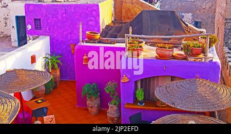 Essaouira, Marocco - Settembre 9. Giorno 2011: Colorato riad viola in stile marocchino sul tetto terrazza ristorante, ombrelloni, tavoli Foto Stock