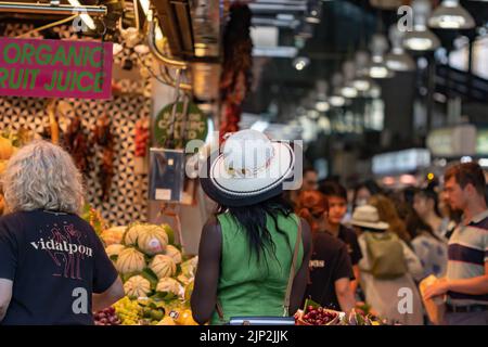 Barcellona, Spagna - 29 giugno 2022: Ragazza con cappello bianco sulla schiena al mercato Boqueria di Barcellona (Spagna), focalizzazione selettiva sul cappello. Foto Stock