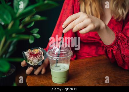 Primo piano torta di ghiaccio e cupcake in un caffè in mani femminili. Foto Stock