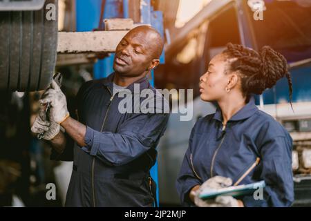 Assistente di garage Nero Africano che lavora insieme per riparare il supporto di ruota di vahicle dell'automobile di servizio insieme Foto Stock