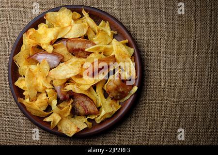 Patatine fritte con pancetta su un piatto su burlap. Primo piano Foto Stock