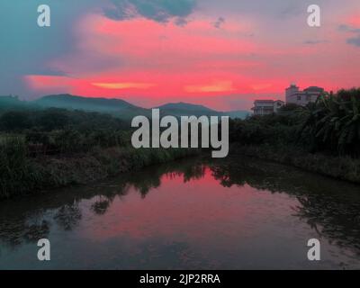 Un cielo rosso, all'alba e un piccolo lago sotto il cielo Foto Stock