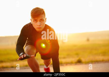 Un giovane uomo sportivo si trova all'inizio del tapis roulant dello stadio Foto Stock