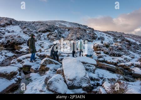 Paesaggi del Regno Unito: Persone che si godono una camminata innevata con un cane su un sentiero su Ilkley Moor nel West Yorkshire, Inghilterra, Regno Unito Foto Stock