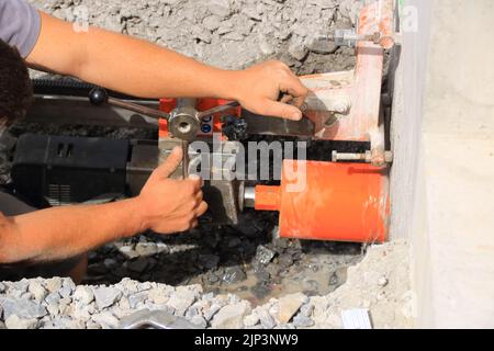 Lavoratore trapana un foro di nucleo in una parete di casa Foto Stock