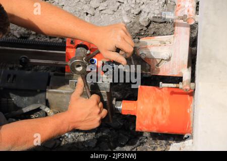 Lavoratore trapana un foro di nucleo in una parete di casa Foto Stock