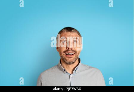 Ritratto dell'uomo maturo eccitato che guarda su sfondo blu Foto Stock
