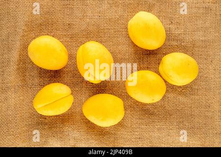 Diverse succose albicocche di ananas gialle luminose su un tovagliolo di iuta, macro, vista dall'alto. Foto Stock