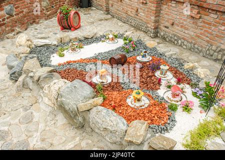 Giardino con tronchi di legno, cesti in vimini, ghiaia e vari ornamenti Foto Stock