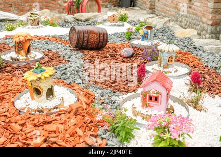 Giardino con tronchi di legno, cesti in vimini, ghiaia e vari ornamenti Foto Stock