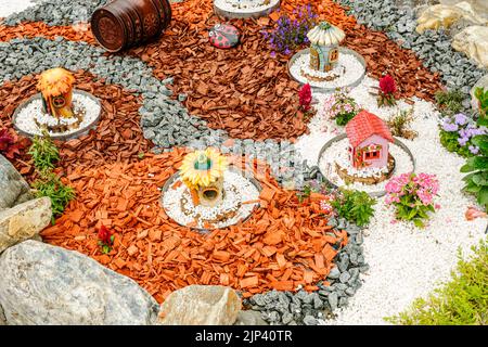 Giardino con tronchi di legno, cesti in vimini, ghiaia e vari ornamenti Foto Stock