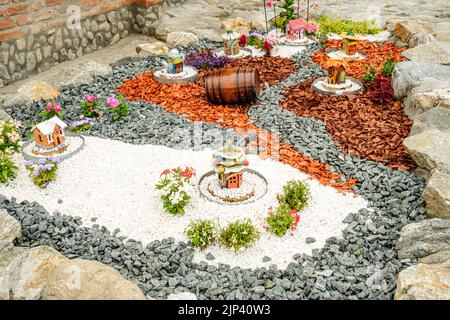 Giardino con tronchi di legno, cesti in vimini, ghiaia e vari ornamenti Foto Stock