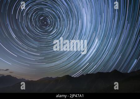 montagne dalle silhouette con sentieri stellari circumpolari nel cielo settentrionale Foto Stock