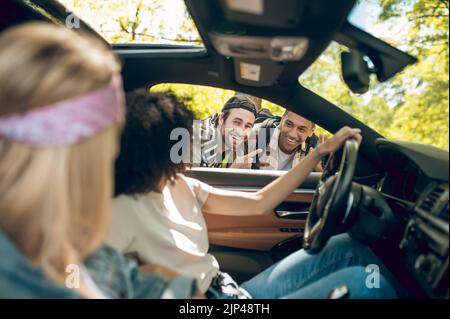 Due uomini che parlano con il conducente e chiedono di prenderli Foto Stock