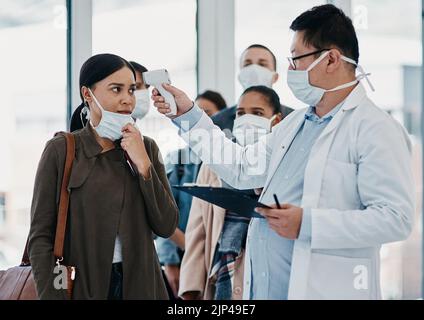 Viaggiare medico operatore sanitario test di temperatura di covid in aeroporto utilizzando termometro a infrarossi. Medico professionista che fa un controllo del coronavirus su Foto Stock