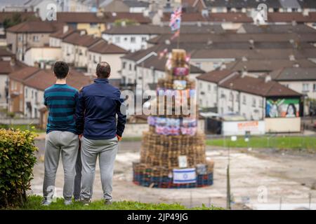 NOTA LA LINGUA SUL BANNER le persone osservano una pila di falò prima che fosse accesa per celebrare la Festa Cattolica dell'Assunzione nell'area di Bogside di Londonderry, Irlanda del Nord. Data immagine: Lunedì 15 agosto 2022. Foto Stock