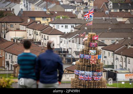 La gente guarda una pila di falò prima che venga accesa per celebrare la festa cattolica dell'Assunzione nella zona di Bogside di Londonderry, Irlanda del Nord. Data immagine: Lunedì 15 agosto 2022. Foto Stock