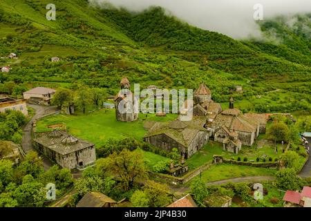 Una vista drone del monastero di Haghpat sulla cima di una collina verde piena di case in Armenia Foto Stock