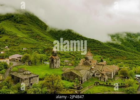 Una vista drone del monastero di Haghpat sulla cima di una collina verde piena di case in Armenia Foto Stock