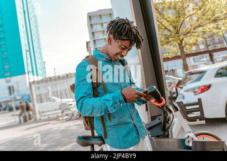 Ragazzo che guarda lo smartphone vicino alla bicicletta Foto Stock