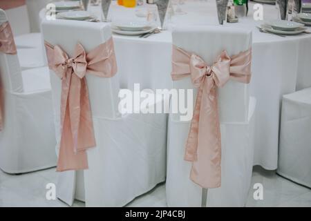 Le sedie bianche da sposa con nastri rosa Foto Stock