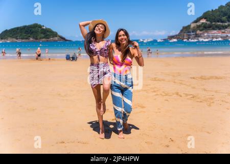 Un primo piano di due sorelle che camminano sulla sabbia e che si godono la vacanza estiva sulla spiaggia Foto Stock