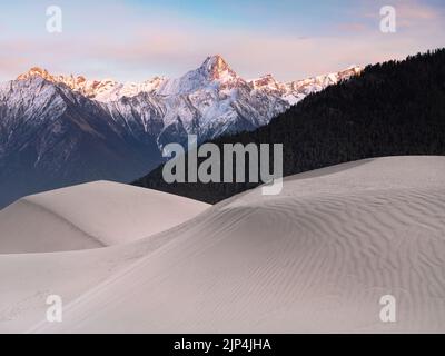 Vista panoramica delle dune di sabbia con montagne innevate sullo sfondo al tramonto nel Grand Canyon di Yarlung Tsangpo, Cina occidentale Foto Stock