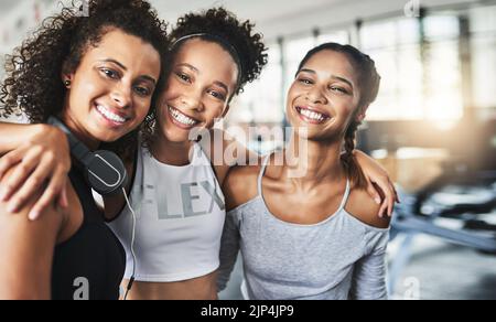 Tutti hanno bisogno di un amico solidale al loro fianco, un gruppo di giovani donne felici che si divertono insieme in palestra. Foto Stock