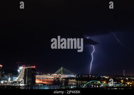 Cielo molto nuvoloso, fulmini e tuoni sopra il cielo di Belgrado (capitale della Serbia), vista panoramica della città e del fiume con ponti. Foto Stock