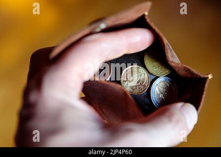 Un portafoglio in pelle con monete Euro in mano da uomo. Foto Stock