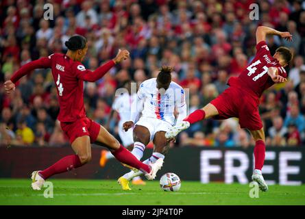 Wilfried Zaha (al centro) del Crystal Palace tenta di sparare la palla oltre Virgil van Dijk (a sinistra) di Liverpool e Nathaniel Phillips durante la partita della Premier League ad Anfield, Liverpool. Data immagine: Lunedì 15 agosto 2022. Foto Stock