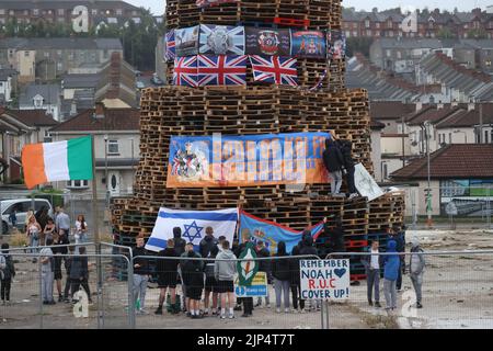 La gente guarda un falò prima di accenderlo per celebrare la festa cattolica dell'Assunzione nella zona di Bogside di Londonderry, Irlanda del Nord. Data immagine: Lunedì 15 agosto 2022. Foto Stock