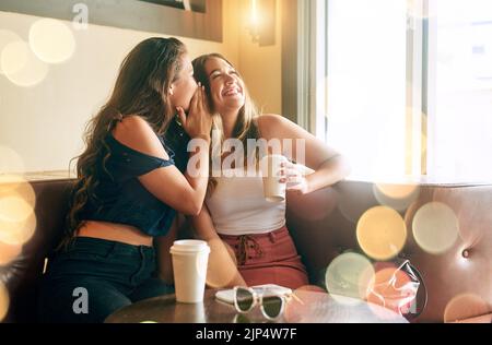 Dandole il lowdown. Due giovani donne attraenti che gossiping nel loro caffè locale. Foto Stock