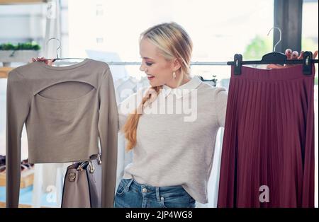 Bella giovane donna sorridente shopping in un moderno negozio di moda, guardando alla moda elegante stili di abbigliamento. Cliente caucasica felice Foto Stock