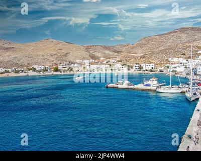 Uno splendido scenario del porto di Karavostasi con barche a vela ed edifici bianchi sotto un cielo nuvoloso Foto Stock