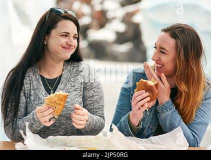 Sono stato qui per mangiare e Buon divertimento. due migliori amici che mangiavano panini in un parco divertimenti all'aperto. Foto Stock