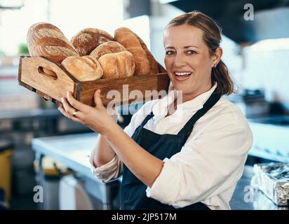 Panettiere, pasticciere e proprietario di caffè che portano un vassoio di panini freschi e assortimento di pane in una caffetteria. Ritratto di un imprenditore di piccola impresa Foto Stock