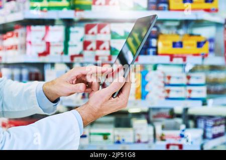 Le app vengono aggiornate più frequentemente degli avvisi sui farmaci cartacei, un farmacista che utilizza un tablet digitale in farmacia. Foto Stock