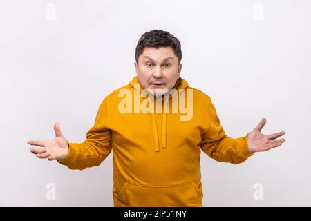 Ritratto di un uomo confuso arrabbiato in piedi con mani sollevate e sorpresa indignata espressione, chiedendo perché, quale motivo, indossare felpa con cappuccio stile urbano. Studio in interni isolato su sfondo bianco. Foto Stock