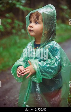 Bambino di charme in un impermeabile nella foresta serale in Danimarca Foto Stock