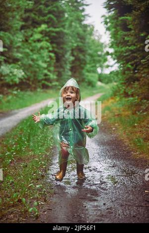 Bambino di charme in un impermeabile nella foresta serale in Danimarca Foto Stock