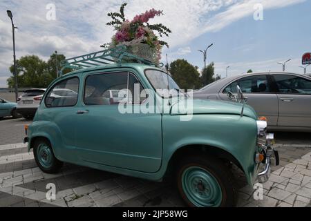 La leggendaria supermini Zastava 750 (Fiat 600) prodotta dal 1955 al 1985 parcheggiata davanti al negozio di fiori, decorata con fiori Foto Stock