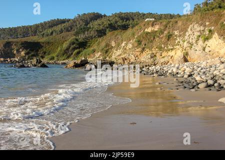 Onde di acqua fredda raggiungono la costa di una spiaggia cantabrica in provincia di Lugo Foto Stock