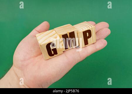Concetto aziendale. Su sfondo verde, nelle mani di una persona, cubi con l'iscrizione - GMP Foto Stock