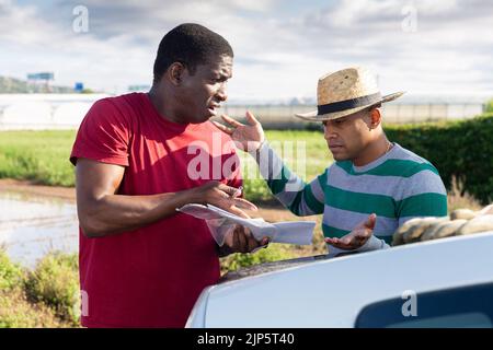 Due coltivatori con carte che discutono sulla fattoria Foto Stock
