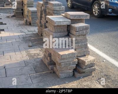 Una pila di piastrelle finitrici a terra. Lavori stradali. Posa di piastrelle sul marciapiede. Lavori di costruzione Foto Stock