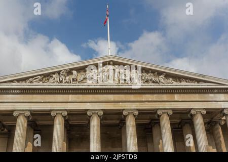 Una vista ad angolo basso dei pilastri d'ingresso al British Museum nel Regno Unito con una bandiera in cima Foto Stock