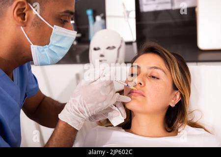 Cliente femminile durante la procedura di mesoterapia del viso in clinica di cosmetologia Foto Stock